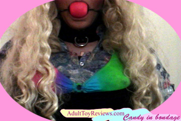 Candy in bondage with ball gag, blonde wig, leather collar, and colorful bra