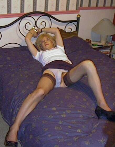 transvestite in panties and cloth miniskirt handcuffed to bed
