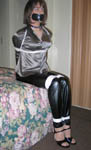 trannie silk blouse, shiny disco pants, and high heels placed in ropes, blindfold, and tape gag